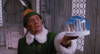 Movie still from “Elf” (2003), directed by Jon Favreau – An old man dressed up as buddy the elf holding a snow globe; Medium shot, Low angle