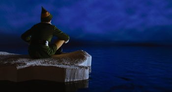 Movie still from “Elf” (2003), directed by Jon Favreau – An elf sitting on top of a box in the middle of the night; Extreme Wide shot, High angle