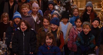 Movie still from “Elf” (2003), directed by Jon Favreau – A group of children standing in front of a christmas tree; Medium shot, High angle