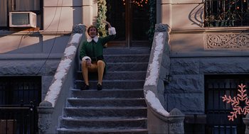 Movie still from “Elf” (2003), directed by Jon Favreau – A man sitting on the steps of a building; Wide shot, Low angle