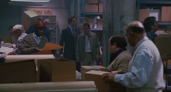 Movie still from “Elf” (2003), directed by Jon Favreau – A group of people standing in a room with boxes on the floor; Medium shot, High angle