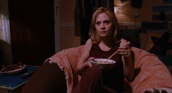 Movie still from “Elf” (2003), directed by Jon Favreau – A woman sitting in a chair holding chopsticks and a bowl of food; Medium shot, High angle
