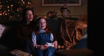Movie still from “Elf” (2003), directed by Jon Favreau – A woman sitting next to a little girl on a couch; Medium shot, Over the shoulder angle