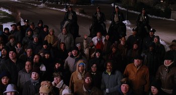 Movie still from “Elf” (2003), directed by Jon Favreau – A large group of people sitting in the snow; Wide shot, High angle