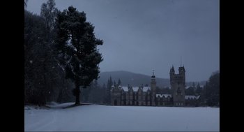 Movie still from “Elizabeth: A Portrait in Part(s)” (2022), directed by Roger Michell – A tree in front of a castle in the middle of snow; Extreme Wide shot, High angle