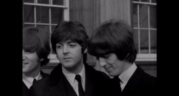 Movie still from “Elizabeth: A Portrait in Part(s)” (2022), directed by Roger Michell – Two men in suits and ties standing next to each other; Close Up shot, High angle