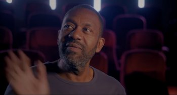 Movie still from “Elizabeth: A Portrait in Part(s)” (2022), directed by Roger Michell – An older man in a theater looking up at the ceiling; Close Up shot, Low angle