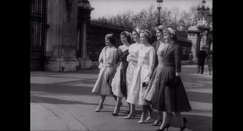 Movie still from “Elizabeth: A Portrait in Part(s)” (2022), directed by Roger Michell – A black and white photo of a group of young women; Wide shot, Low angle