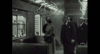 Movie still from “Elizabeth: A Portrait in Part(s)” (2022), directed by Roger Michell – A man and a woman on a subway train; Wide shot, High angle