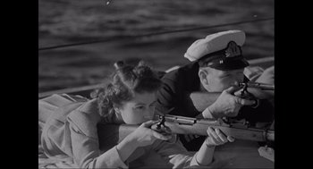 Movie still from “Elizabeth: A Portrait in Part(s)” (2022), directed by Roger Michell – A man and a woman holding a rifle; Medium shot, Low angle