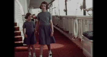 Movie still from “Elizabeth: A Portrait in Part(s)” (2022), directed by Roger Michell – Two young girls standing on the deck of a boat; Medium shot, High angle