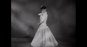 Movie still from “Elizabeth: A Portrait in Part(s)” (2022), directed by Roger Michell – An old photo of a woman wearing a dress; Medium shot, Low angle