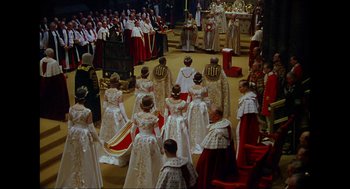 Movie still from “Elizabeth: A Portrait in Part(s)” (2022), directed by Roger Michell – A group of people standing in a room; Extreme Wide shot, High angle