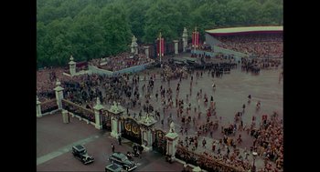 Movie still from “Elizabeth: A Portrait in Part(s)” (2022), directed by Roger Michell – An aerial view of a crowd of people walking around a park; Extreme Wide shot, High angle