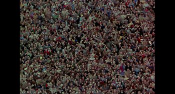 Movie still from “Elizabeth: A Portrait in Part(s)” (2022), directed by Roger Michell – A large crowd of people gathered together in a stadium; Extreme Wide shot, Overhead angle