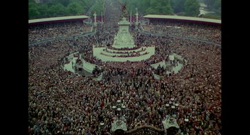 Movie still from “Elizabeth: A Portrait in Part(s)” (2022), directed by Roger Michell – An aerial view of a crowd of people gathered in a park; Extreme Wide shot, High angle