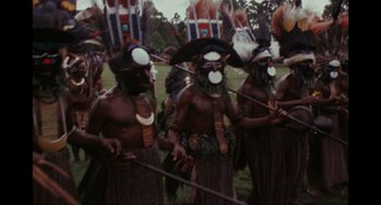 Movie still from “Elizabeth: A Portrait in Part(s)” (2022), directed by Roger Michell – A group of men in traditional dress are standing in a field; Medium shot, High angle