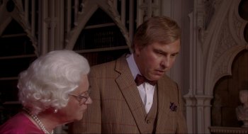 Movie still from “Elizabeth: A Portrait in Part(s)” (2022), directed by Roger Michell – An older man in a suit and a bow tie standing next to an older woman in glasses; Close Up shot, Over the shoulder angle