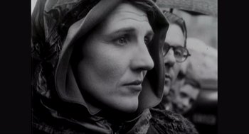 Movie still from “Elizabeth: A Portrait in Part(s)” (2022), directed by Roger Michell – An old photo of a woman wearing a hood; Close Up shot, Over the shoulder angle