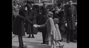 Movie still from “Elizabeth: A Portrait in Part(s)” (2022), directed by Roger Michell – An old photo of a man and a little girl shaking hands; Medium shot, High angle