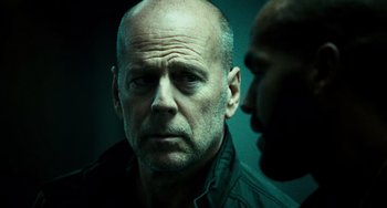 Movie still from “A Good Day to Die Hard” (2013), directed by John Moore – A man with a beard and a black shirt is looking at another man with a beard; Close Up shot, Low angle