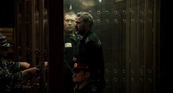 Movie still from “A Good Day to Die Hard” (2013), directed by John Moore – Two men are standing in front of a glass door; Medium shot, Over the shoulder angle