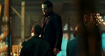 Movie still from “A Good Day to Die Hard” (2013), directed by John Moore – A man in a suit standing in front of two other men; Medium shot, Over the shoulder angle