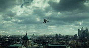 Movie still from “A Good Day to Die Hard” (2013), directed by John Moore – A helicopter flying over a large city under a cloudy sky; Extreme Wide shot, High angle