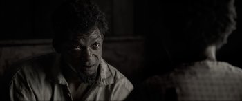 Movie still from “Emancipation” (2022), directed by Antoine Fuqua – A black and white photo of a man with a beard; Close Up shot, High angle