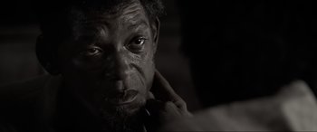 Movie still from “Emancipation” (2022), directed by Antoine Fuqua – An old man with a beard is looking at the camera; Close Up shot, Over the shoulder angle