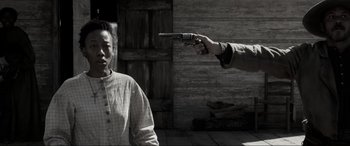 Movie still from “Emancipation” (2022), directed by Antoine Fuqua – A man holding a gun in front of another man; Medium shot, Over the shoulder angle
