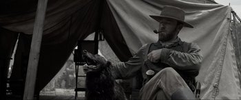 Movie still from “Emancipation” (2022), directed by Antoine Fuqua – A man sitting with a dog in front of a tent; Medium shot, Low angle