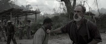 Movie still from “Emancipation” (2022), directed by Antoine Fuqua – An old man touching the neck of a young man; Medium shot, Over the shoulder angle
