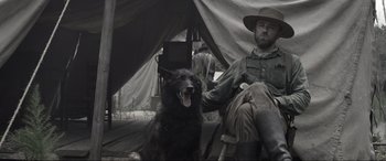 Movie still from “Emancipation” (2022), directed by Antoine Fuqua – A man sitting in a chair with a black dog; Medium shot, Low angle