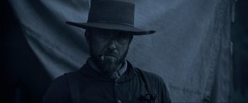 Movie still from “Emancipation” (2022), directed by Antoine Fuqua – A man with a beard and a hat is smoking a cigarette; Close Up shot, Low angle