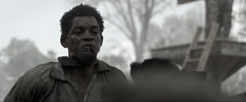 Movie still from “Emancipation” (2022), directed by Antoine Fuqua – A black and white photo of a man with a beard; Close Up shot, Over the shoulder angle
