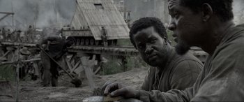 Movie still from “Emancipation” (2022), directed by Antoine Fuqua – A man sitting on the side of a river; Close Up shot, Over the shoulder angle