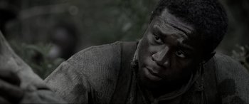 Movie still from “Emancipation” (2022), directed by Antoine Fuqua – A black man with dirt all over his face; Close Up shot, Over the shoulder angle
