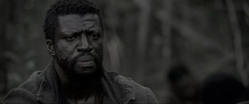 Movie still from “Emancipation” (2022), directed by Antoine Fuqua – A man with a black beard is looking at the camera; Close Up shot, Low angle