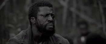 Movie still from “Emancipation” (2022), directed by Antoine Fuqua – A black and white photo of a man with a beard; Close Up shot, Low angle
