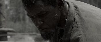 Movie still from “Emancipation” (2022), directed by Antoine Fuqua – A black and white photo of a man with a beard; Close Up shot, High angle