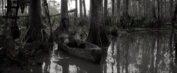 Movie still from “Emancipation” (2022), directed by Antoine Fuqua – A man sitting in a canoe in the middle of a swamp; Wide shot, High angle