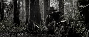 Movie still from “Emancipation” (2022), directed by Antoine Fuqua – A man and a dog sitting in the woods; Wide shot, Over the shoulder angle