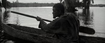 Movie still from “Emancipation” (2022), directed by Antoine Fuqua – A black and white photo of a man rowing a boat on a lake; Medium shot, Low angle