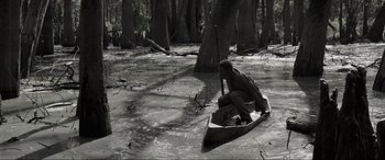 Movie still from “Emancipation” (2022), directed by Antoine Fuqua – A man sitting in a canoe in a swamp; Wide shot, High angle