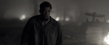 Movie still from “Emancipation” (2022), directed by Antoine Fuqua – A black and white photo of a man in a black shirt; Medium shot, Low angle