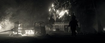 Movie still from “Emancipation” (2022), directed by Antoine Fuqua – A person standing in front of a house on fire; Extreme Wide shot, Low angle