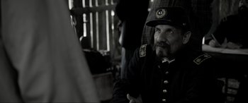 Movie still from “Emancipation” (2022), directed by Antoine Fuqua – A man in a uniform sitting in front of a wooden fence; Close Up shot, Over the shoulder angle