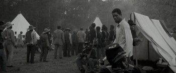 Movie still from “Emancipation” (2022), directed by Antoine Fuqua – A black and white photo of a group of men standing in a field; Medium shot, Over the shoulder angle