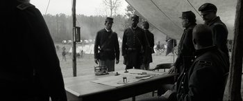 Movie still from “Emancipation” (2022), directed by Antoine Fuqua – A group of men standing next to each other in a field; Wide shot, Over the shoulder angle
